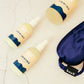 A travel kit featuring a blue sleep eye mask, hand sanitizer, and moisturizing lotion in a toiletry bag