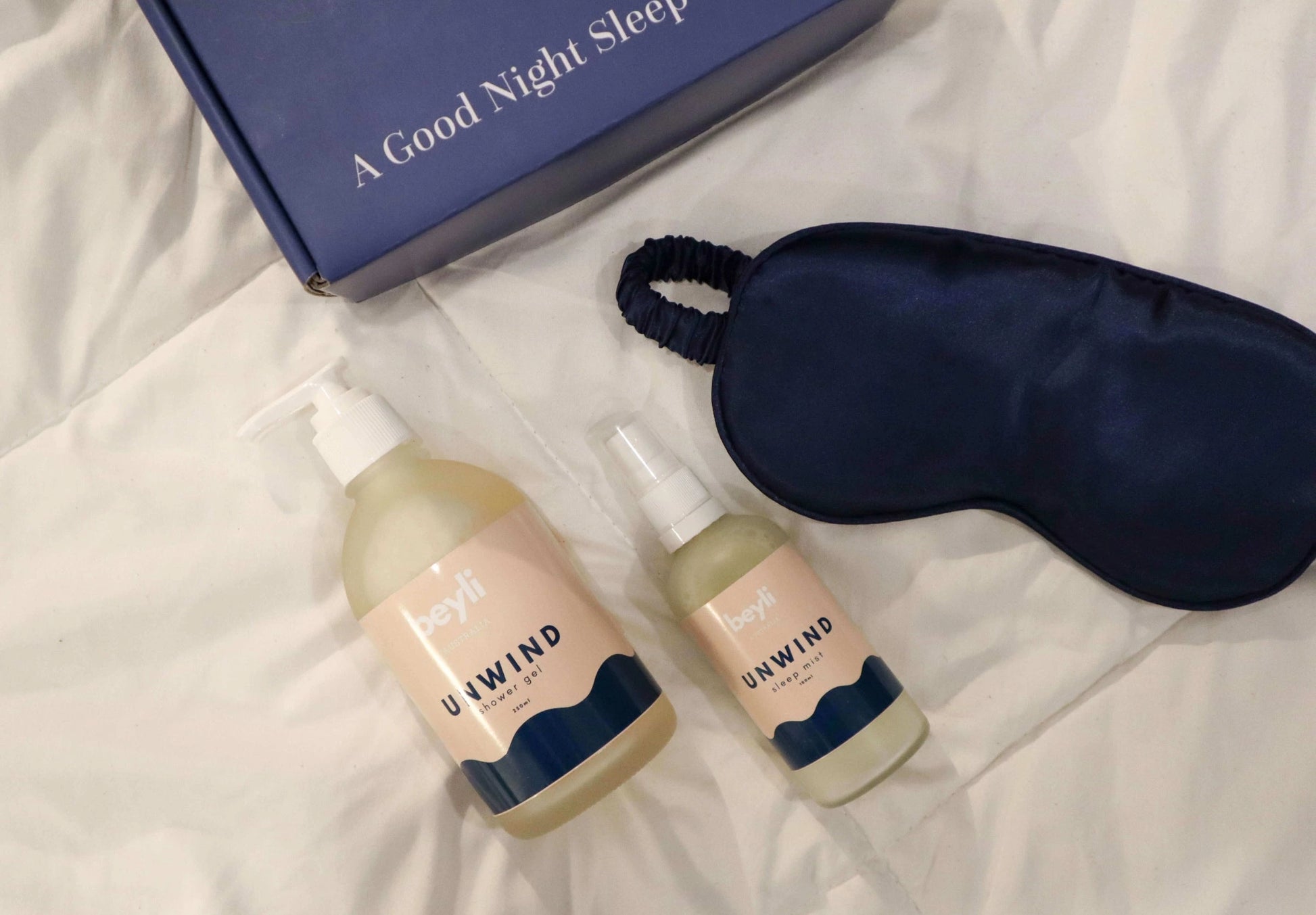 A sleep improvement kit featuring a mist and a blue eye mask on a nightstand