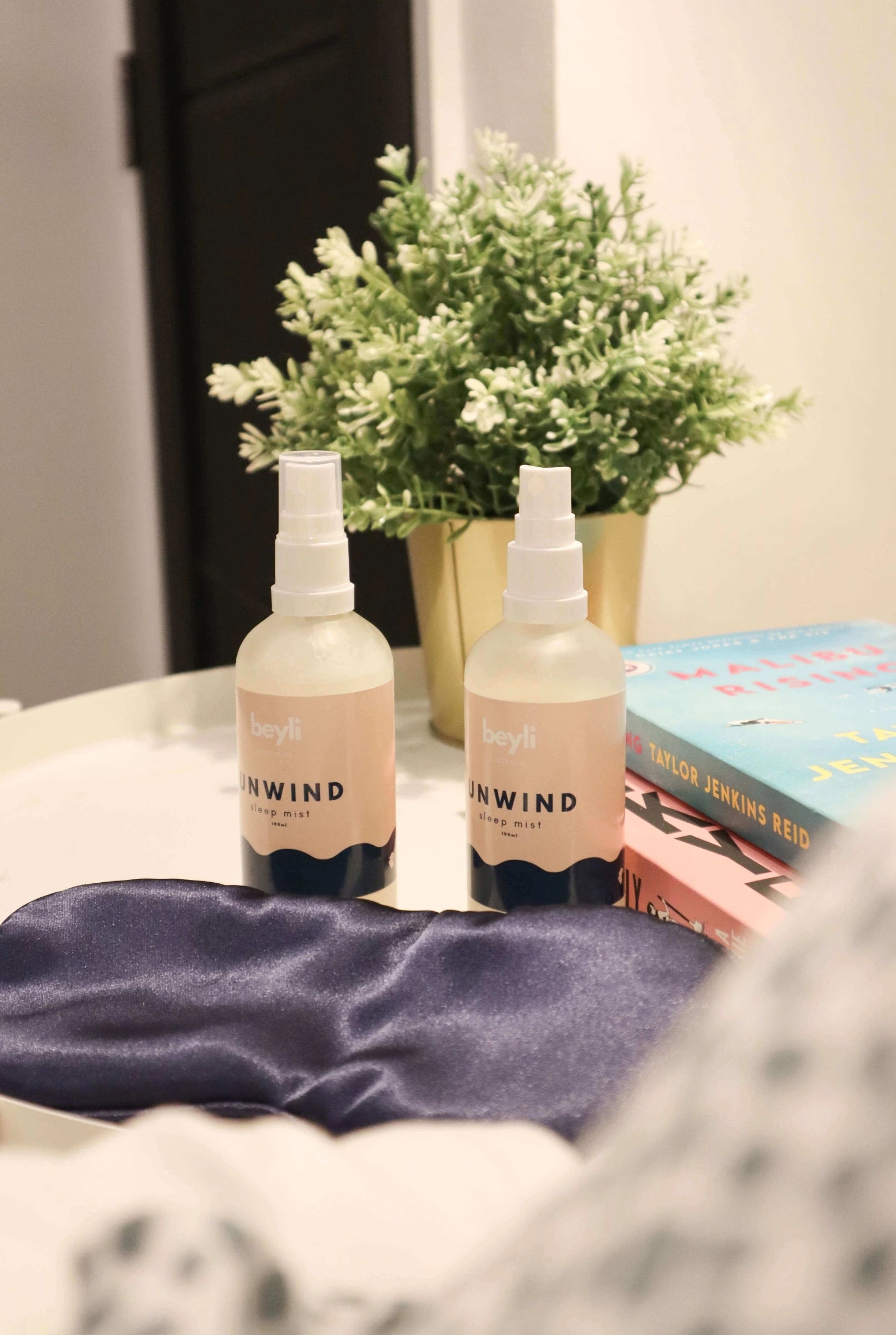 A nighttime routine set with sleep mist and a book on a bedside surface