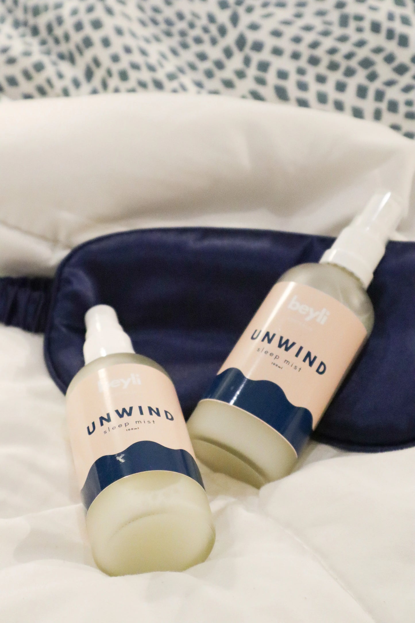 Pair of Sleep Bundle Essentials unwind lotions on a comfortable bed