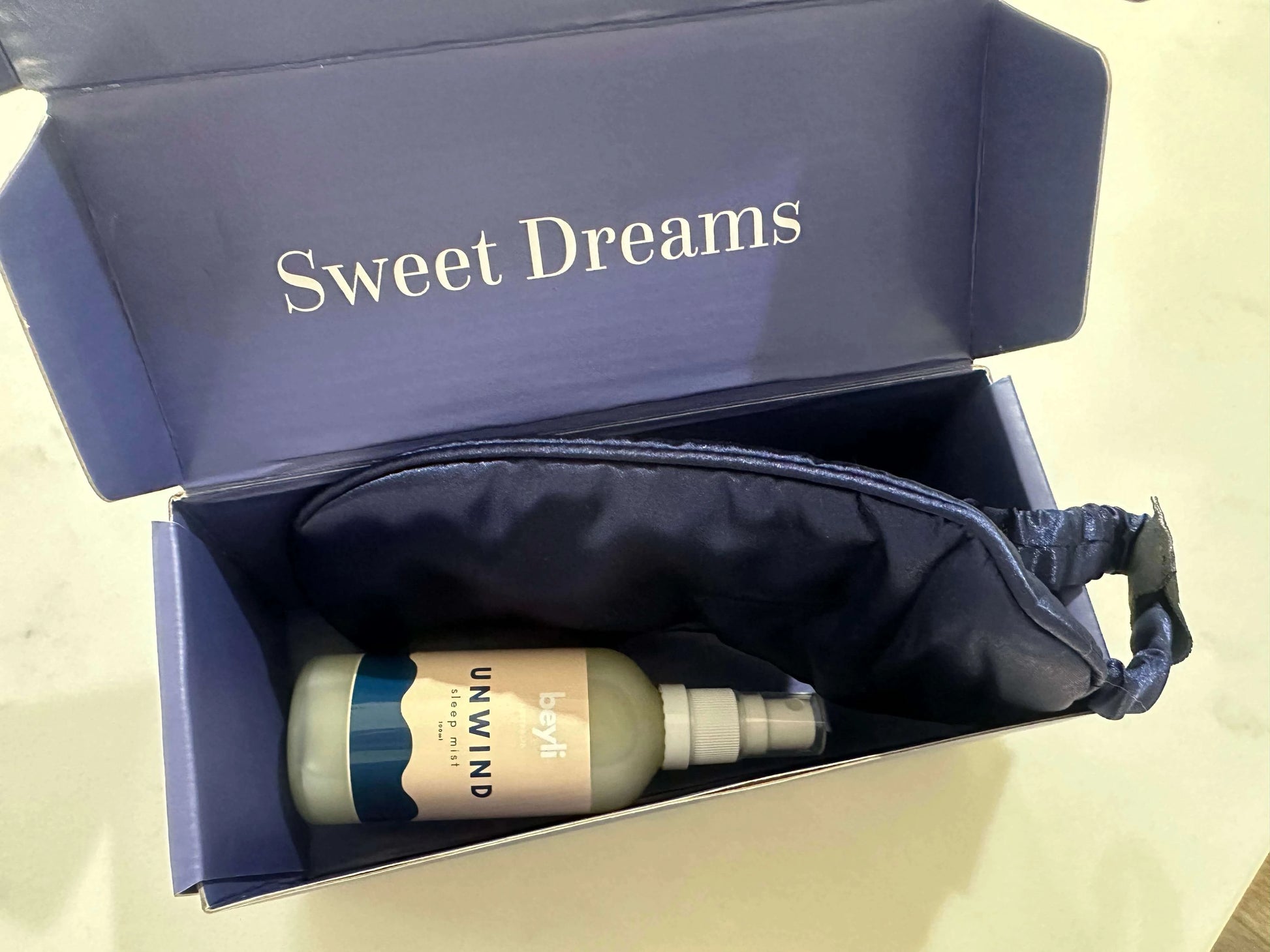 A luxurious blue package containing the Better Sleep Mist and a matching sleep mask