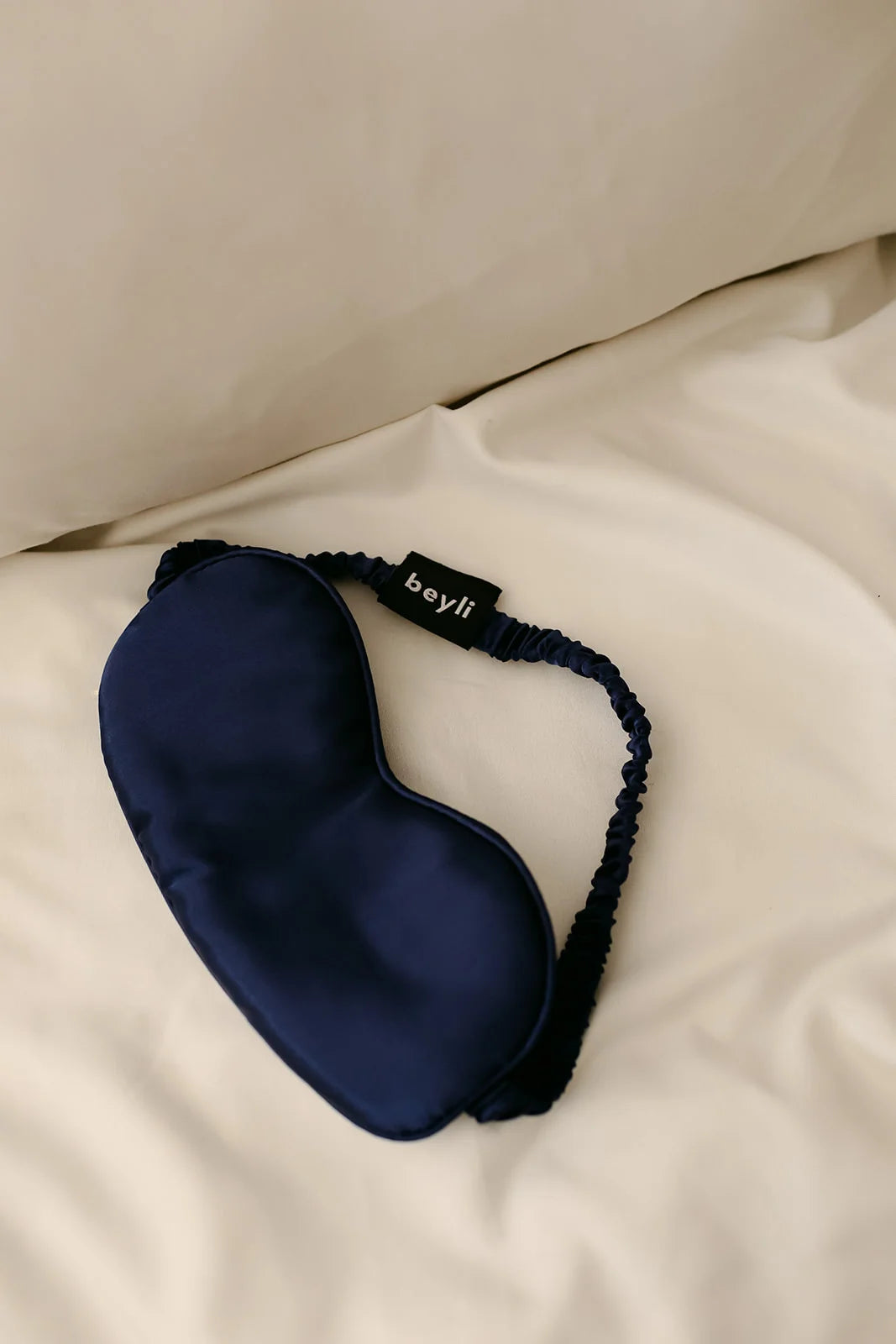 A single blue memory foam eye mask designed for sleep on a white pillow