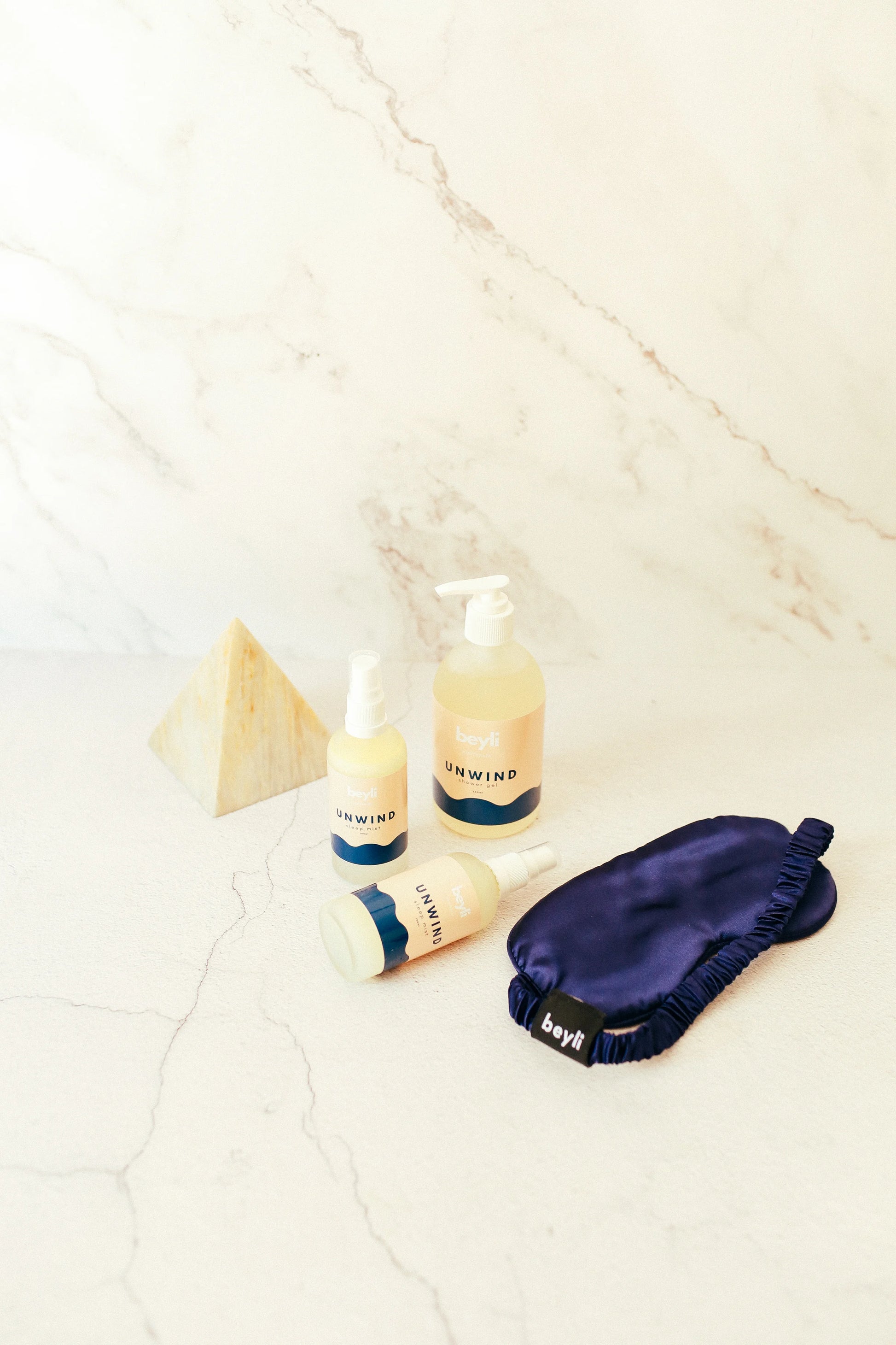 A relaxing sleep eye mask paired with hand cream and lotion on a bedside table
