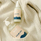 Sleep Bundle Essentials hand lotion duo beside a cozy white sweater